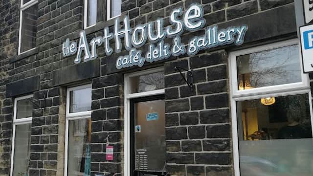The ArtHouse Cafe features a stone facade with large windows and a sign displaying its name, cafe, deli, and gallery.