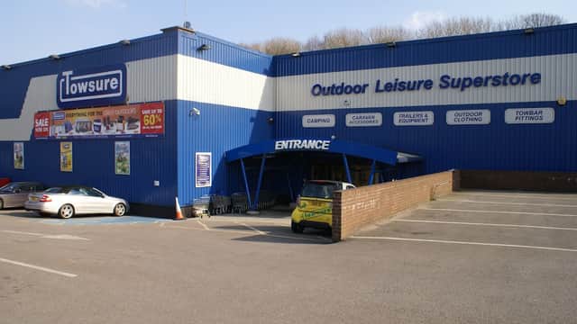 Blue building with "Towsure" sign, parking lot, and entrance; features outdoor leisure products and sales signage.