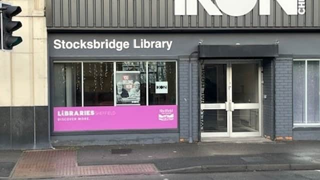 Stocksbridge Library storefront with large windows, a pink sign, and the adjacent IKON Church building.