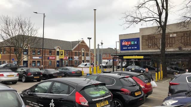 Pay & Display parking area with several cars, a building in the background, and a large advertising sign.