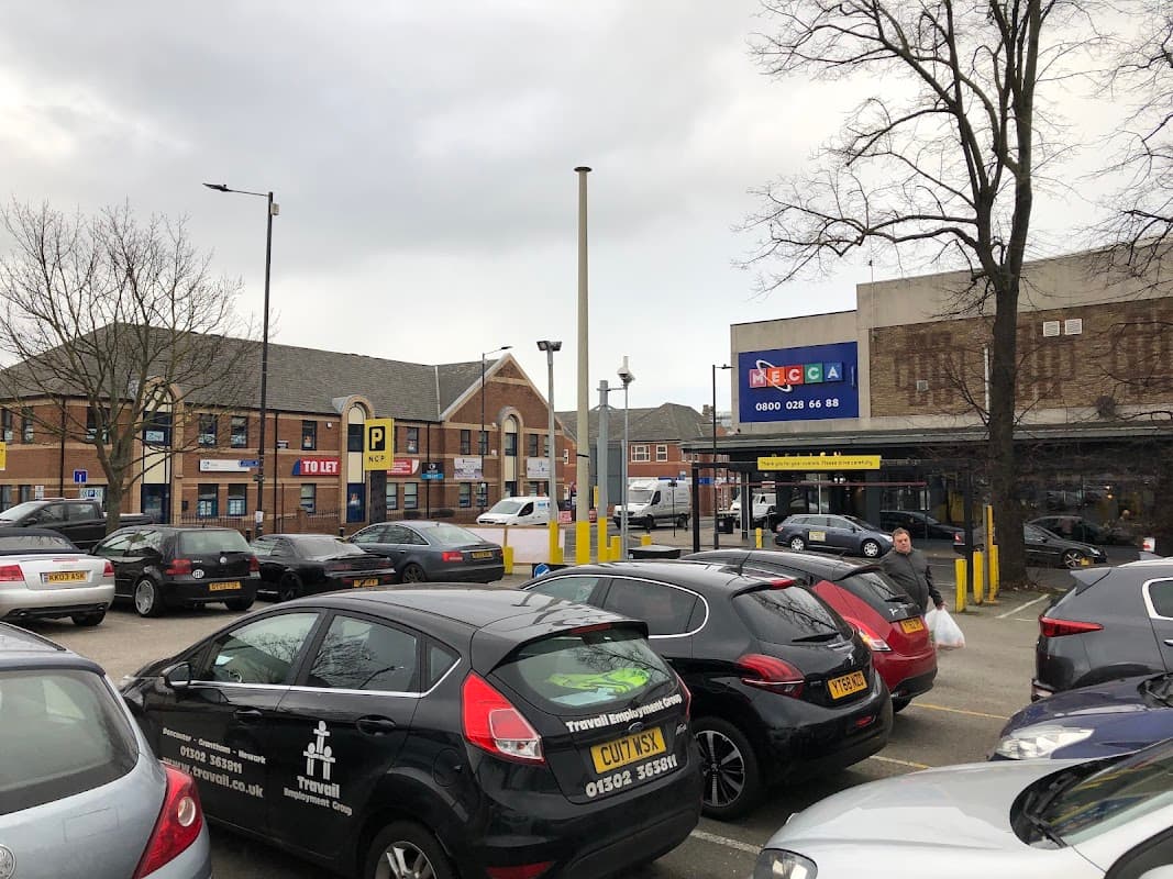 Pay & Display parking area with several cars, a building in the background, and a large advertising sign.