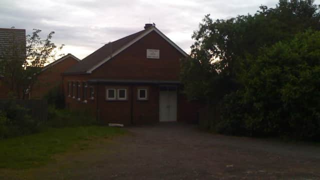 Brick building with a sign reading "Darby & Joan Club," surrounded by greenery and a gravel pathway.