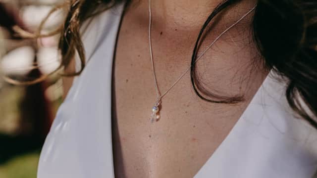 Delicate silver necklace with a small pendant, worn on a bare collarbone, highlighting a natural, elegant look.
