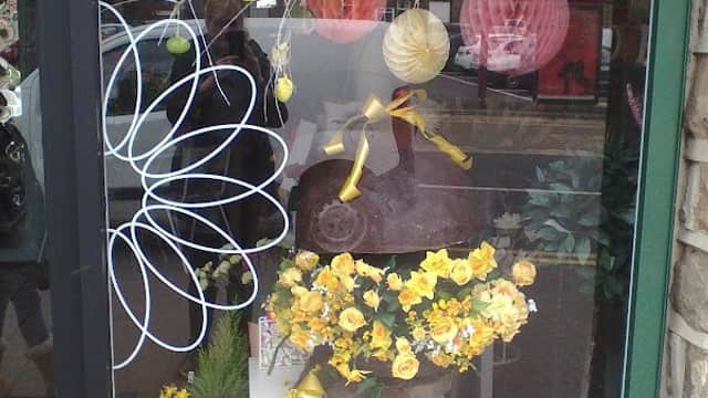 Colorful flower arrangements in a shop window, with decorative paper lanterns and cheerful floral designs.
