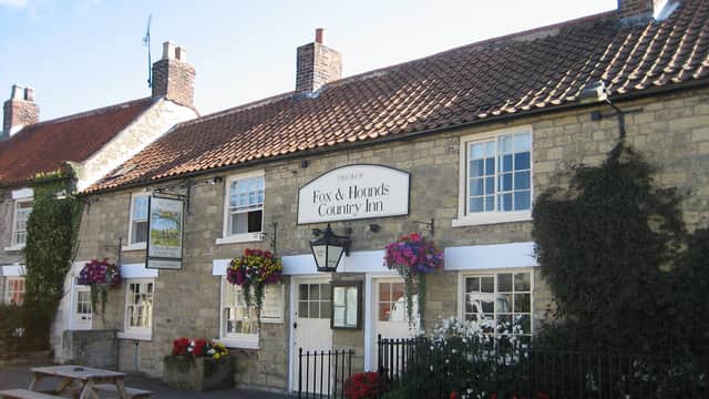 Charming stone country inn with flower baskets, ivy-covered walls, and a traditional red-tiled roof.