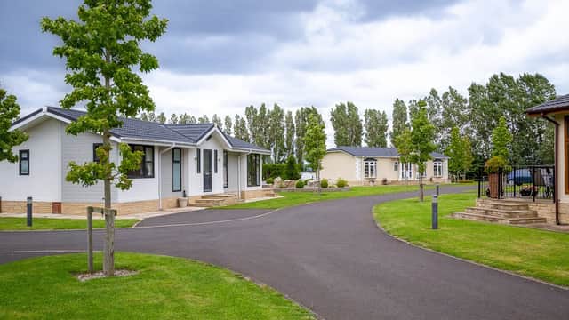 Holiday park featuring modern lodges, well-maintained lawns, and lined trees under a cloudy sky in Hutton Rudby.