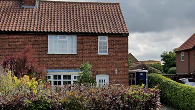 Ebor Equine Therapy building with a red-tiled roof, surrounded by greenery and a gravel driveway under a cloudy sky.