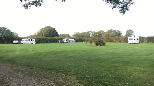 Caravan site with several caravans parked on a lush green lawn, surrounded by trees and hedges in Cropton, Yorkshire.