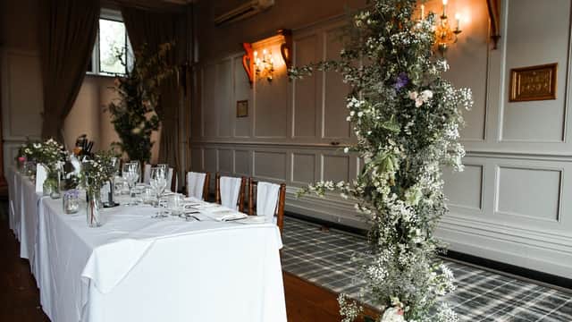 Elegant floral arrangements adorn a beautifully set dining table in a stylish venue with soft lighting and wooden floors.