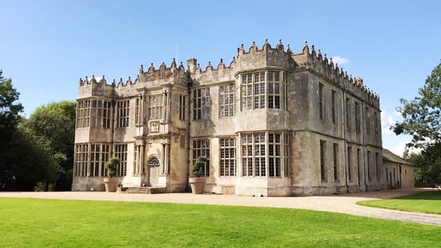 Historic Howsham Hall features ornate stone architecture, large windows, and manicured lawns under a clear blue sky.