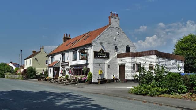 Chequers Inn hotel with a white exterior, red roof, outdoor seating, and lush greenery in Dalton-on-Tees, Yorkshire.