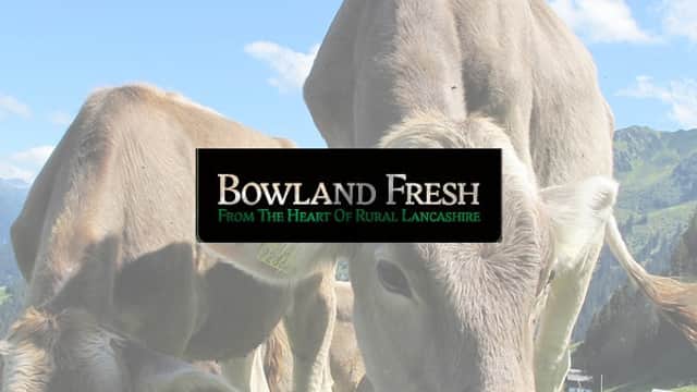 Cows grazing in a green field with a blue sky and mountains in the background; "Bowland Fresh" logo overlay.