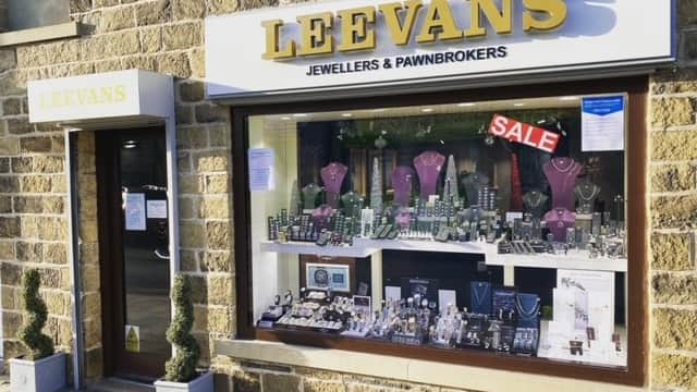 Jewellery shop display featuring necklaces, watches, and a "SALE" sign, with stone building exterior.