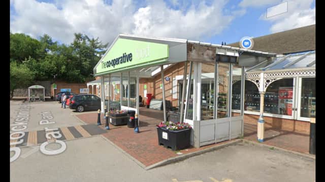 Co-operative food store entrance with a car park, flower planters, and blue sky in Bolsterstone, Yorkshire.