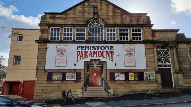 Historic cinema building with large "Penistone Paramount" sign, decorative stonework, and a blue sky backdrop.