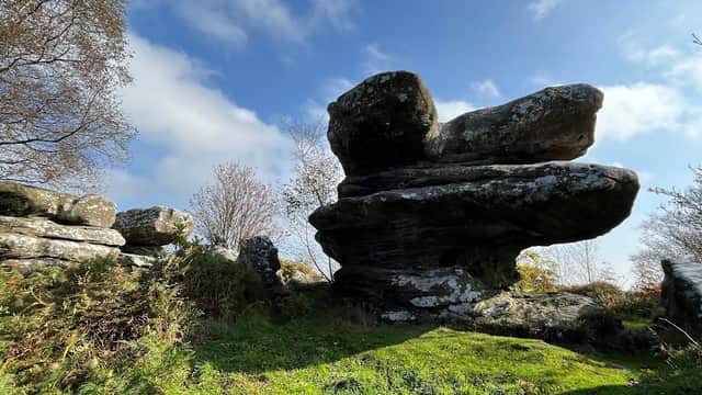 Unique rock formations surrounded by greenery under a partly cloudy sky at Brimham Rocks Car Park.