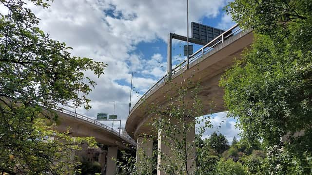 Curved overpass with traffic signs, surrounded by trees and a partly cloudy sky in Halifax, Yorkshire.