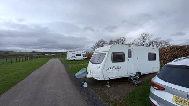 Caravans parked along a gravel path, with green fields and cloudy skies in the background at Brigholme Farm.