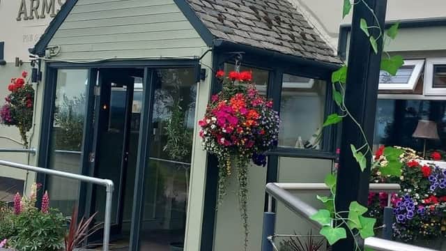 The Kaye Arms features a charming entrance with vibrant flower baskets and a cozy porch area.