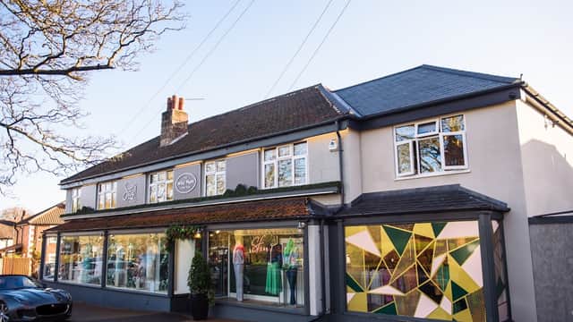 Department store exterior with large windows showcasing colorful dresses and modern geometric patterns.