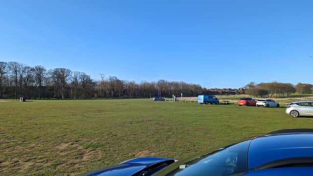 Limekiln Lane Car Park features grassy areas, parked cars, and trees under a clear blue sky in Bridlington, Yorkshire.