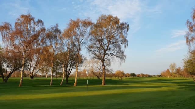 Lush green golf course at Bawtry Golf Club, lined with trees under a clear blue sky.