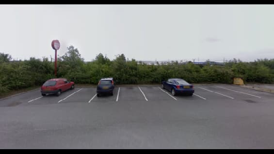 Pay & Display parking area in Birstall, Yorkshire, with three parked cars and overgrown greenery in the background.
