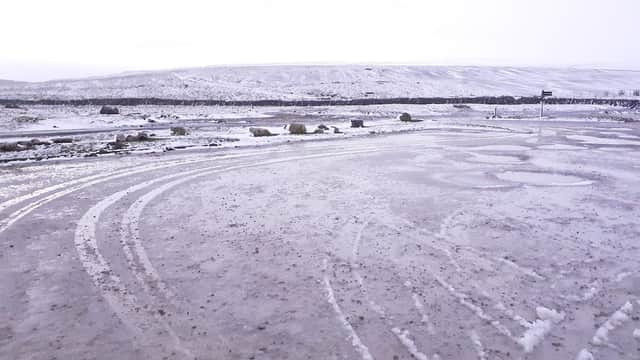 Free parking area with wet, snowy ground and distant hills under a cloudy sky in Thornton, Craven, Yorkshire.