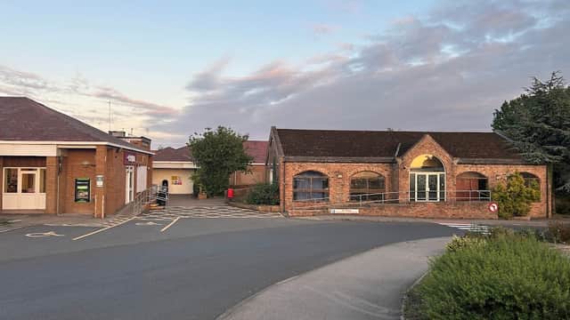 Moto Leeming Bar shop with brick facade, adjacent buildings, parking area, and trees under a colorful sky.