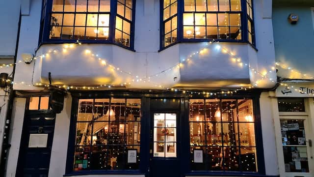 Charming pub exterior with blue window frames, warm lights, and festive string lights adorning the facade.
