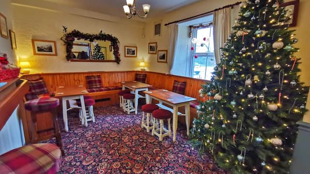 Cozy bar interior with festive Christmas tree, wooden furniture, and warm lighting in Embsay, Yorkshire.
