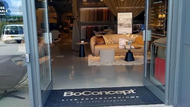 Entrance to BoConcept store with stylish furniture displays and a welcoming mat on the ground.