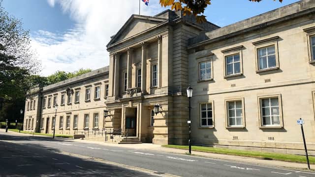 Crescent Gardens in Harrogate features a grand stone building with a flag, surrounded by greenery and a clear blue sky.