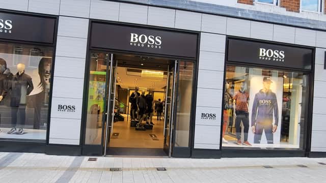 BOSS store entrance featuring stylish mannequins, modern decor, and large glass windows showcasing clothing displays.