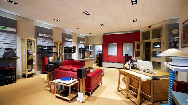 Modern homeware store interior featuring red seating, audio equipment displays, and a workspace with a computer.