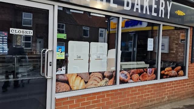 Shopfront of Nisa Local with a bakery sign, featuring a display of various baked goods. Door shows "CLOSED" sign.