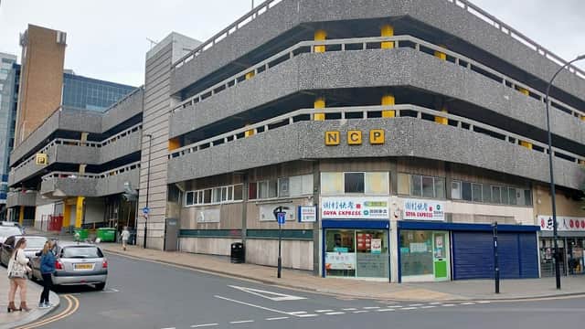 NCP parking garage with gray concrete structure, yellow accents, and nearby shops on Furnival Gate, Sheffield.
