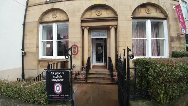 Entrance of Boutique 25 bar with stone facade, large windows, and a sign promoting stylish stayovers.