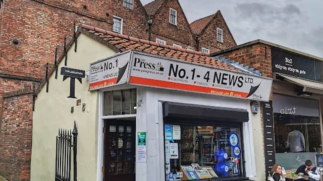 Quaint bookshop "No 1 4 News" with a colorful window display, surrounded by historic brick buildings in York.