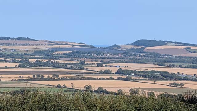 Rolling hills and patchwork fields under a clear blue sky, with distant coastal views in Staxton, Yorkshire.