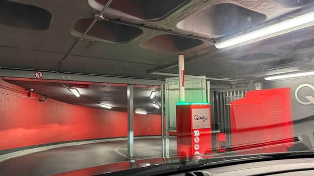 Interior of Q-Park Albion Street with a red wall, parking barrier, and illuminated signage in a multi-storey car park.