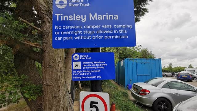 Sign for Tinsley Marina car park with rules, blue container in background, and a parking sign indicating a speed limit.