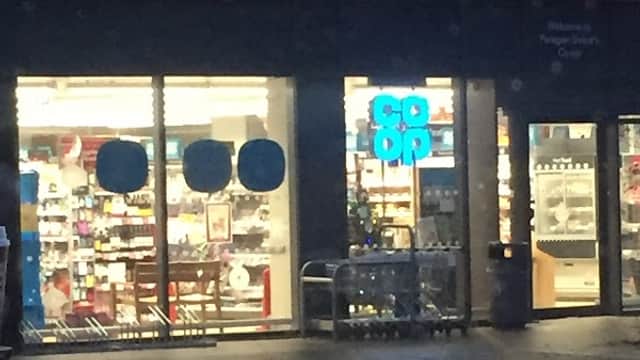 Co-op Food storefront on Paragon Street, illuminated at night, showcasing products through large glass windows.