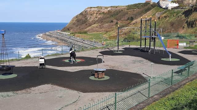 Play park with swings, climbing structures, and a view of the sea and cliffs in Scarborough, Yorkshire.