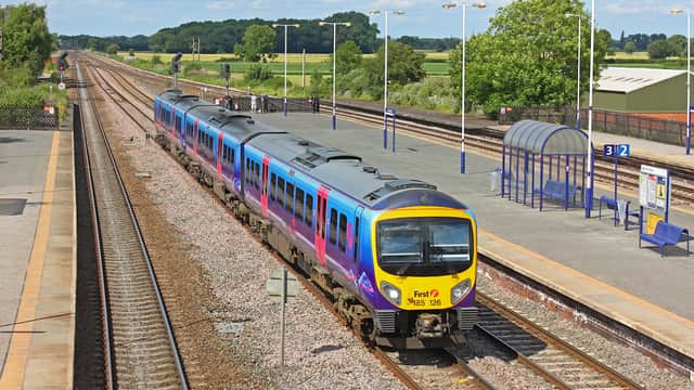 A train approaches Church Fenton station, with green fields and a clear blue sky in the background.