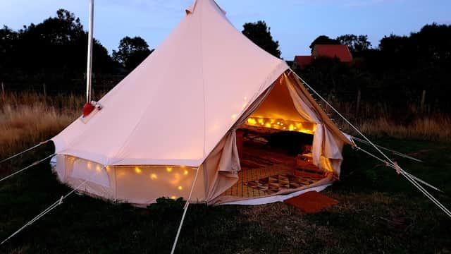 A cozy glamping tent with warm string lights, set in a grassy field at Clover Hill Farm, North Yorkshire.
