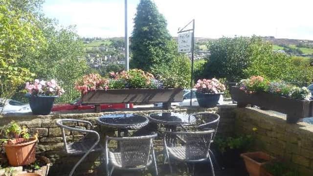 Outdoor seating area with a table and chairs surrounded by flower pots and scenic views of the Yorkshire countryside.