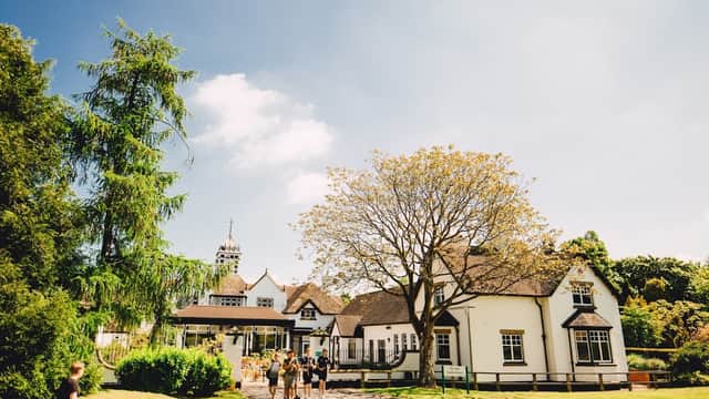 Bishop Burton College's charming venue features a large tree, lush greenery, and a historic building under a blue sky.