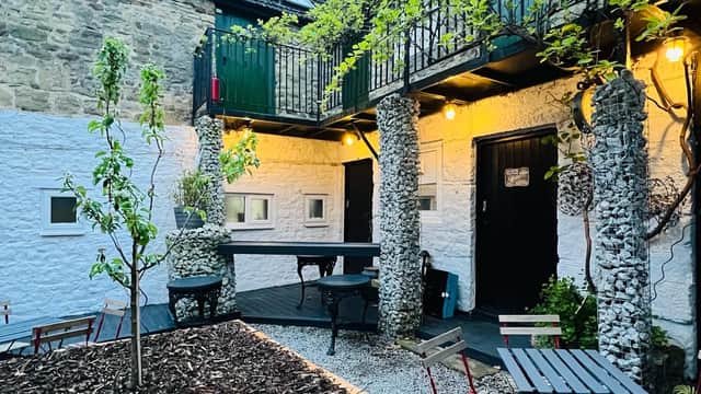Charming courtyard with stone walls, greenery, outdoor seating, and warm lighting at Stable Yard Rooms in Gilling West.