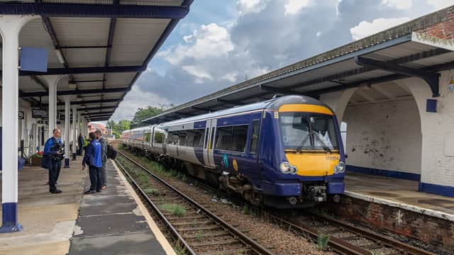 A train at Driffield Railway Station with passengers waiting on the platform under a cloudy sky.